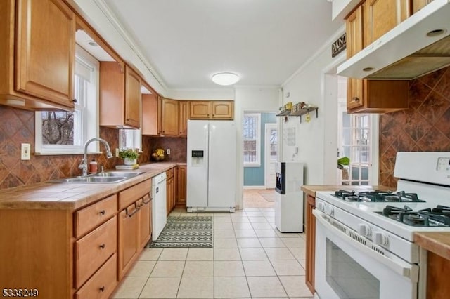 kitchen featuring under cabinet range hood, a sink, tile countertops, white appliances, and light tile patterned floors