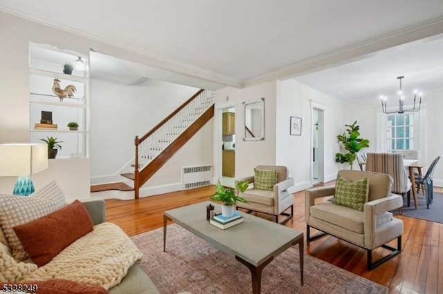 living area featuring radiator, crown molding, stairway, a notable chandelier, and wood-type flooring