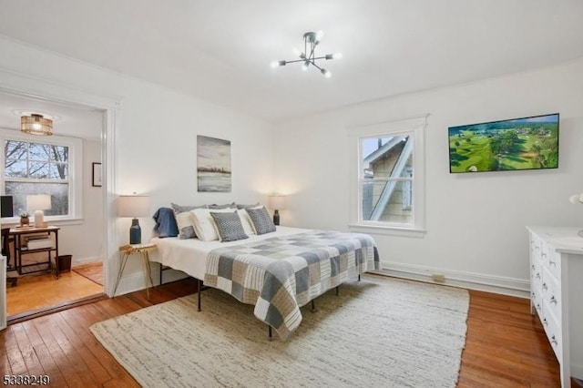 bedroom with baseboards, an inviting chandelier, and hardwood / wood-style floors