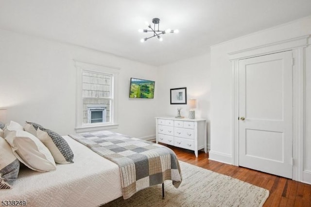 bedroom with a notable chandelier, wood finished floors, and baseboards