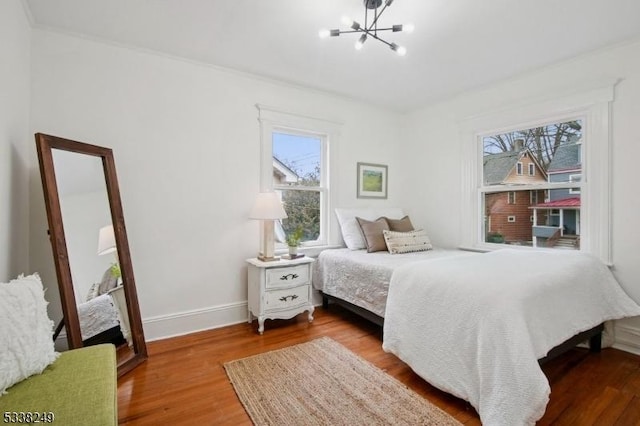 bedroom featuring an inviting chandelier, multiple windows, and wood finished floors