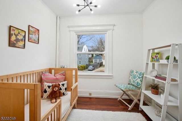 bedroom with baseboards, a notable chandelier, wood finished floors, and ornamental molding