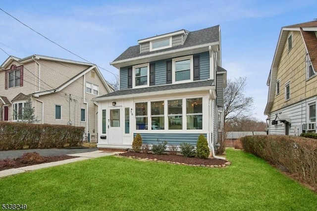 american foursquare style home featuring a front lawn and a shingled roof