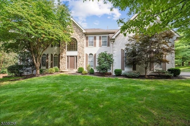 view of front of home featuring stone siding, a front lawn, and stucco siding