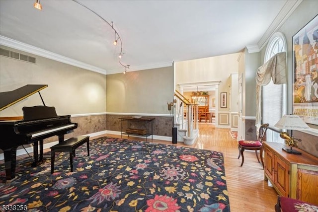 living area with visible vents, a wainscoted wall, stairway, ornamental molding, and light wood-style floors