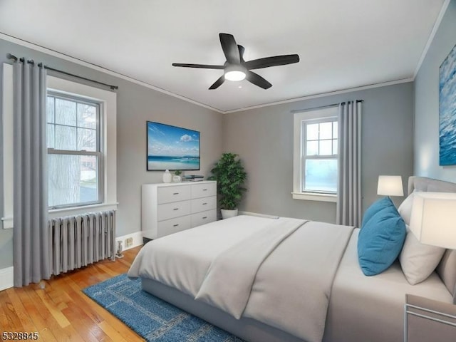 bedroom featuring crown molding, radiator heating unit, ceiling fan, and light wood-type flooring