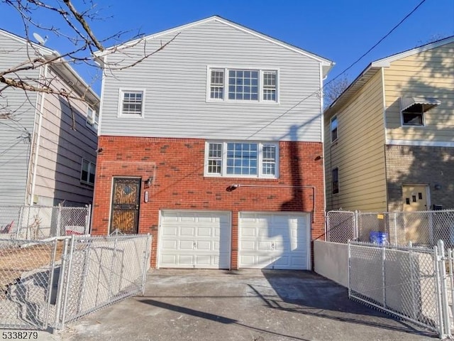 rear view of house featuring a garage, brick siding, concrete driveway, and fence