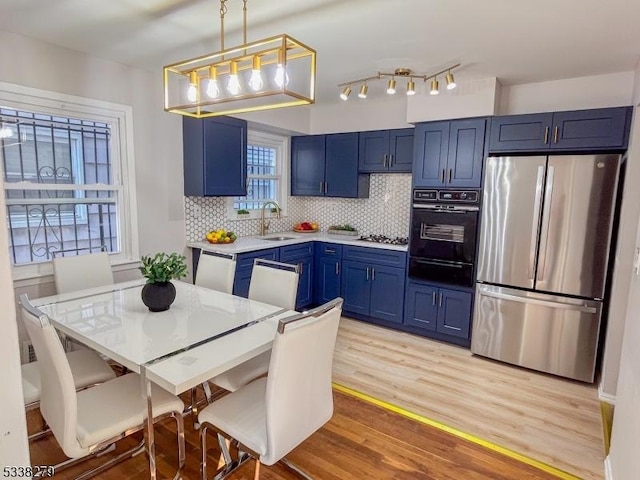 kitchen featuring a warming drawer, a sink, blue cabinetry, appliances with stainless steel finishes, and light countertops