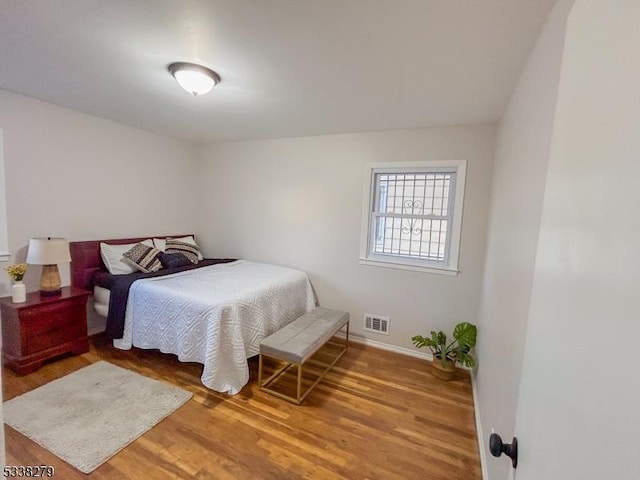 bedroom featuring wood finished floors, visible vents, and baseboards