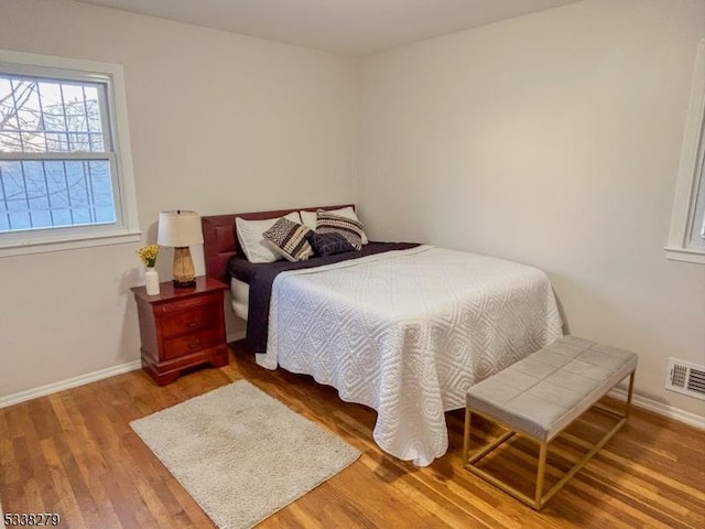 bedroom featuring visible vents, baseboards, and wood finished floors