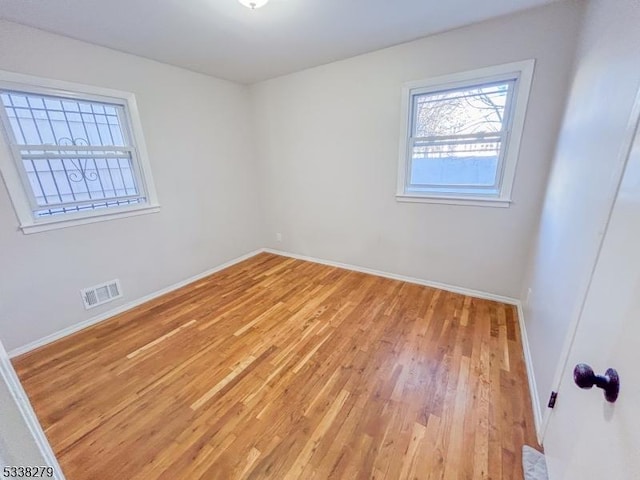 spare room with visible vents, light wood-style flooring, and baseboards