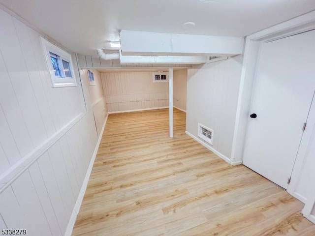 below grade area with light wood-style floors and visible vents