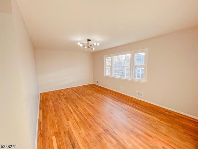 empty room with visible vents, baseboards, light wood-style floors, and a notable chandelier