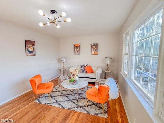 living area featuring a chandelier, baseboards, and wood finished floors