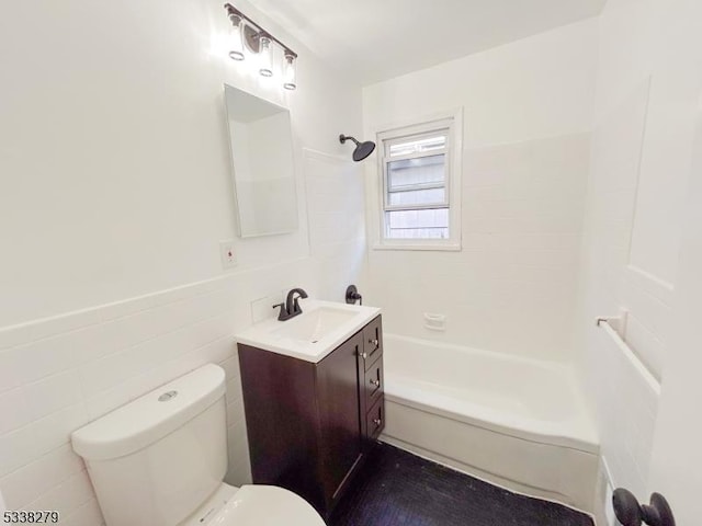 full bath with a wainscoted wall, toilet, shower / tub combination, tile walls, and vanity