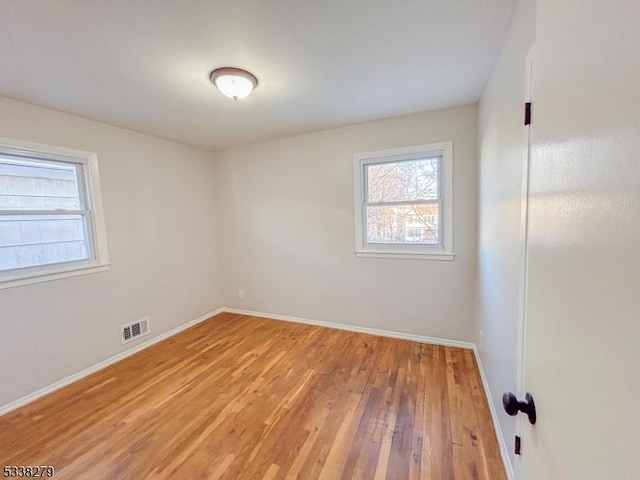 empty room featuring visible vents, baseboards, and light wood finished floors