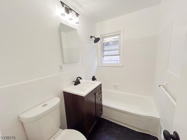 full bath featuring tile walls, toilet, shower / bath combination, wainscoting, and vanity