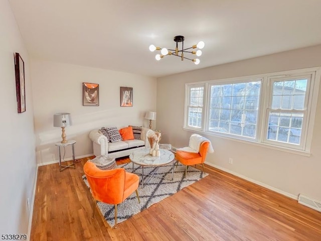 living room with visible vents, baseboards, an inviting chandelier, and wood finished floors