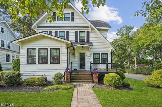 view of front of property with roof with shingles and a front lawn