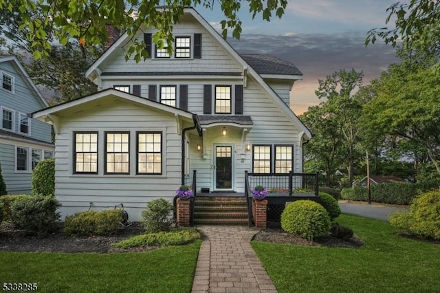 view of front of house featuring roof with shingles and a front yard