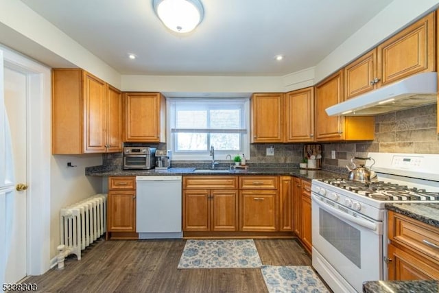 kitchen with sink, tasteful backsplash, radiator heating unit, dark hardwood / wood-style flooring, and white appliances