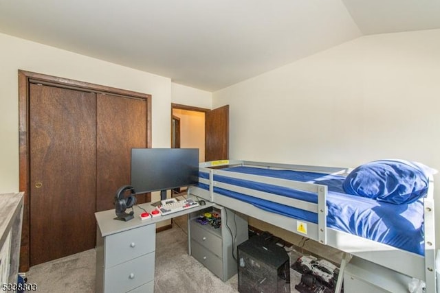 carpeted bedroom with vaulted ceiling and a closet