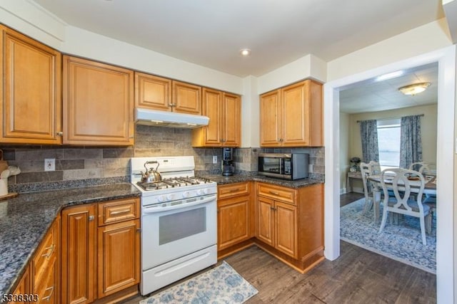 kitchen with white range with gas cooktop, dark hardwood / wood-style flooring, decorative backsplash, and dark stone countertops