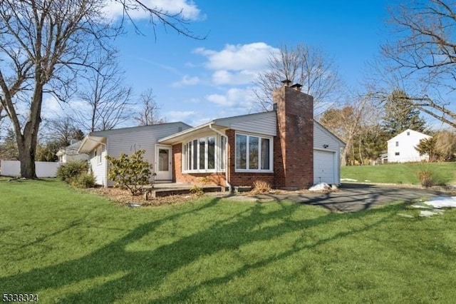 view of front of home with a chimney, brick siding, a front lawn, and an attached garage