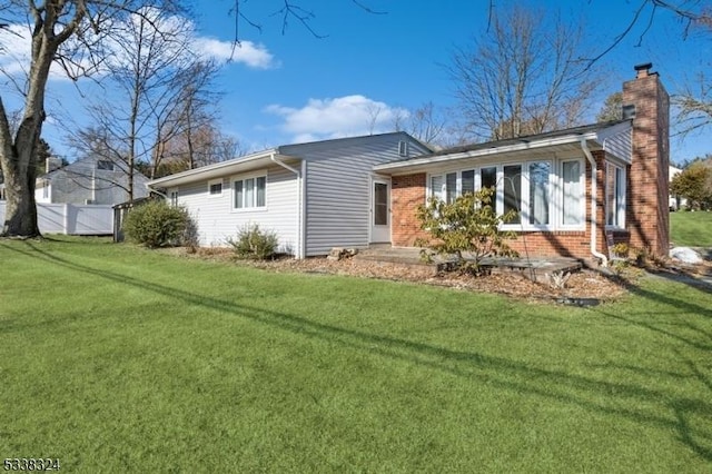 view of property exterior with brick siding, a lawn, and a chimney