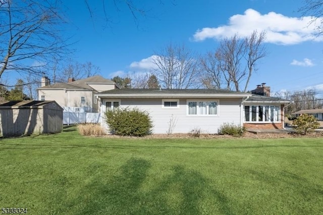 back of house featuring brick siding, a chimney, a lawn, a storage shed, and an outdoor structure