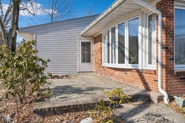 exterior space with brick siding and a patio area