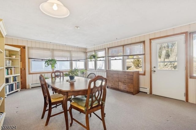 dining space featuring wood walls, a baseboard heating unit, and light colored carpet