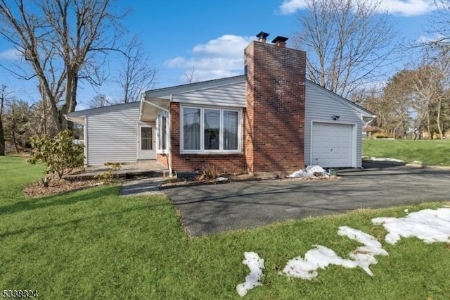 exterior space with an attached garage, brick siding, driveway, a chimney, and a front yard