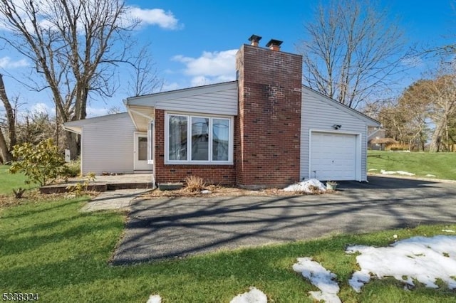 view of property exterior with driveway, brick siding, a lawn, and an attached garage