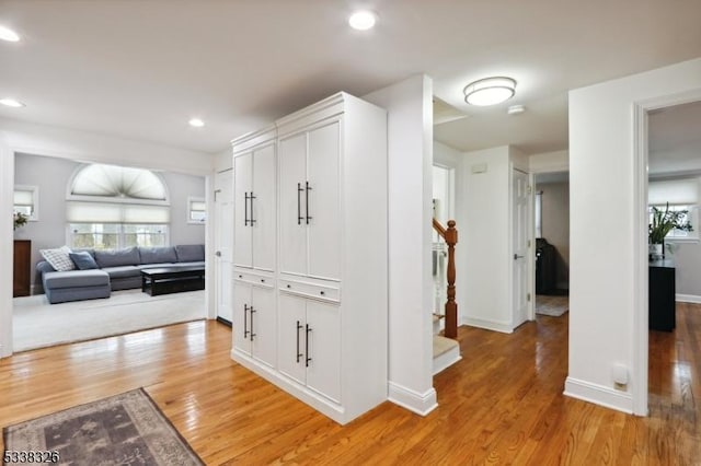 hallway featuring light wood-style floors, stairs, baseboards, and recessed lighting