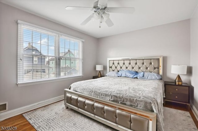 bedroom featuring visible vents, light wood finished floors, a ceiling fan, and baseboards