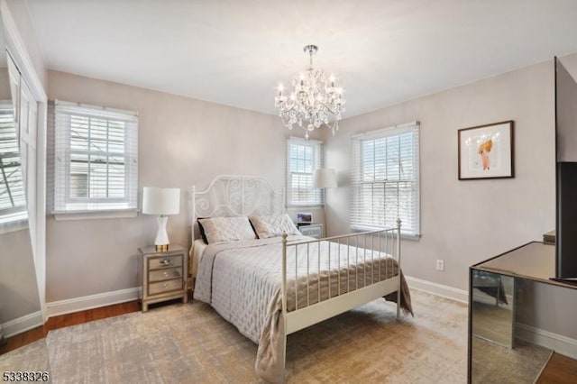 bedroom with a chandelier, baseboards, and wood finished floors