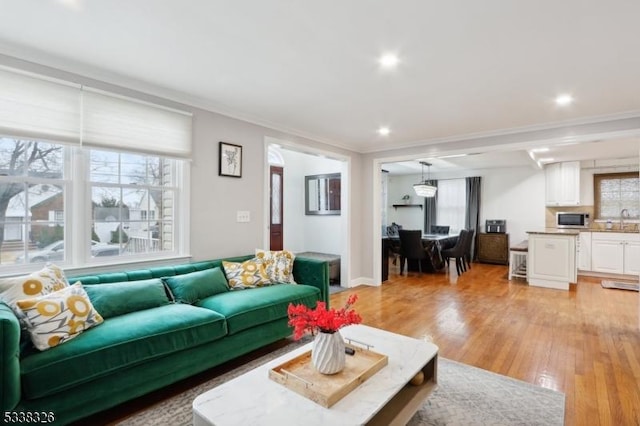 living room with plenty of natural light, recessed lighting, light wood-type flooring, and crown molding