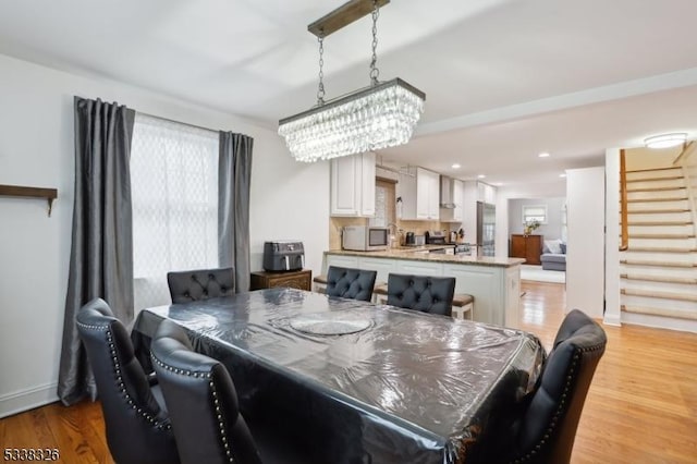 dining space featuring light wood-type flooring, baseboards, recessed lighting, and stairs