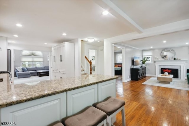 kitchen with light stone countertops, white cabinetry, and open floor plan