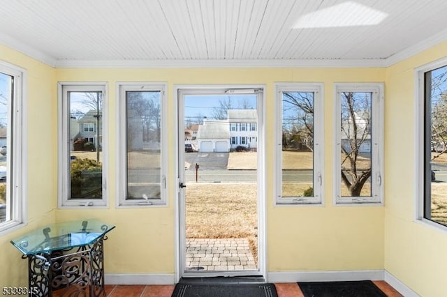 doorway with ornamental molding, tile patterned flooring, and baseboards