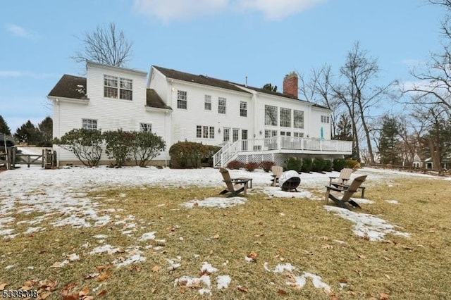 rear view of house with an outdoor fire pit, a chimney, and a wooden deck