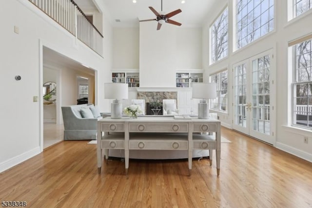 living area with a towering ceiling, a fireplace, baseboards, and wood finished floors