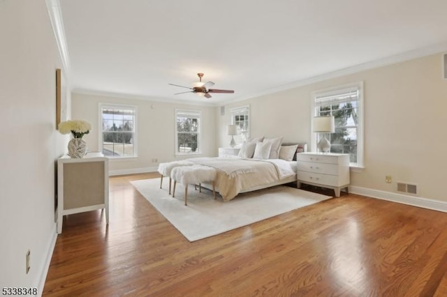 bedroom with baseboards, visible vents, ornamental molding, and wood finished floors