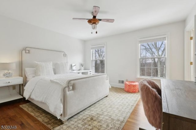 bedroom featuring ceiling fan, wood finished floors, visible vents, and baseboards