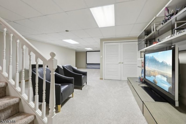 living area featuring stairway, a drop ceiling, and carpet flooring