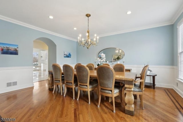 dining area featuring arched walkways, wood finished floors, visible vents, plenty of natural light, and crown molding