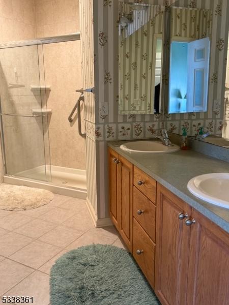 bathroom featuring tile patterned flooring, vanity, and walk in shower