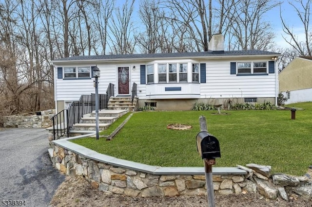 ranch-style home featuring entry steps, driveway, a chimney, and a front yard