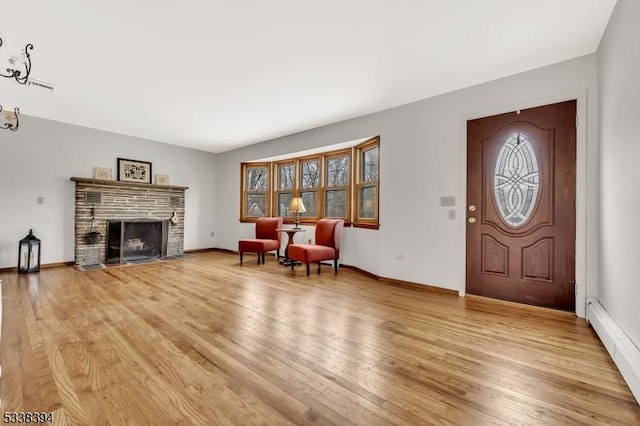 foyer featuring a brick fireplace, baseboards, and light wood finished floors